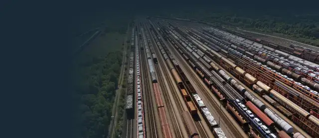 High-angle view of multiple freight trains and shipping containers in a large rail yard.